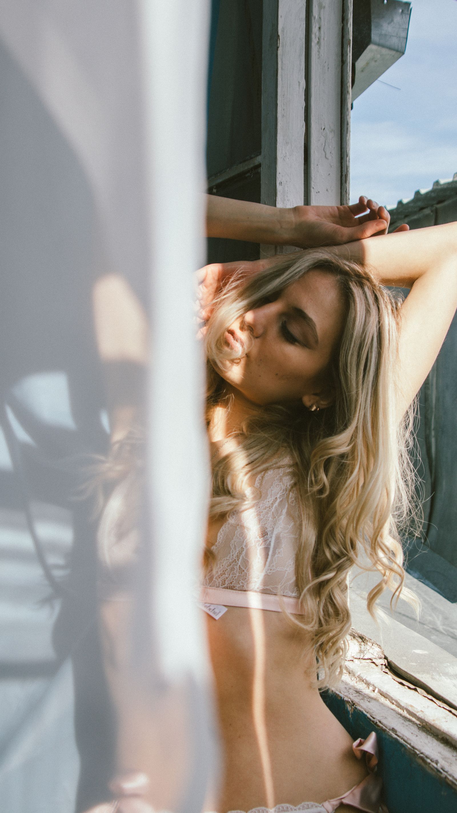 Woman resting beside a sheer curtain in natural light