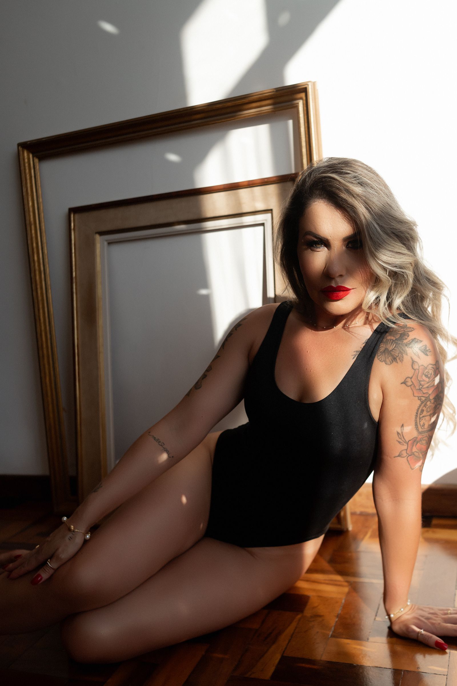 Woman in a black bodysuit seated in a sunlit room